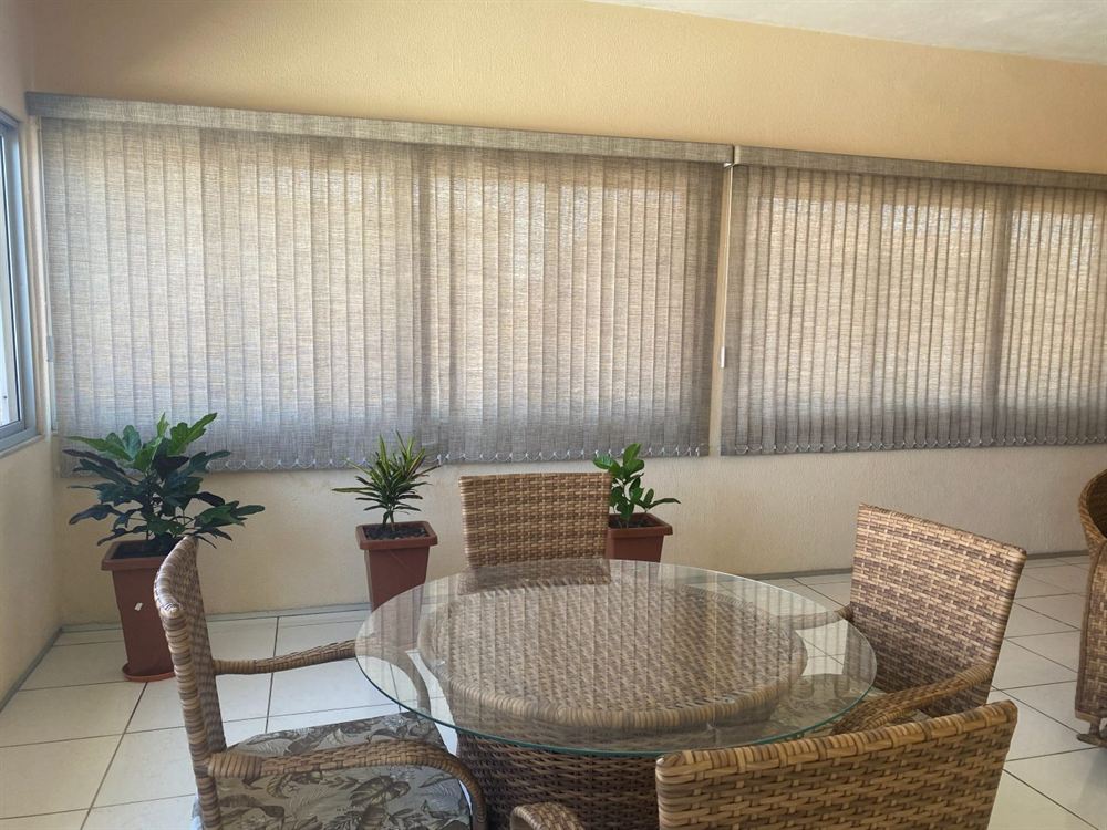 Cortinas em varanda com mesa de vidro, projeto da EDD Cortinas em Fortaleza